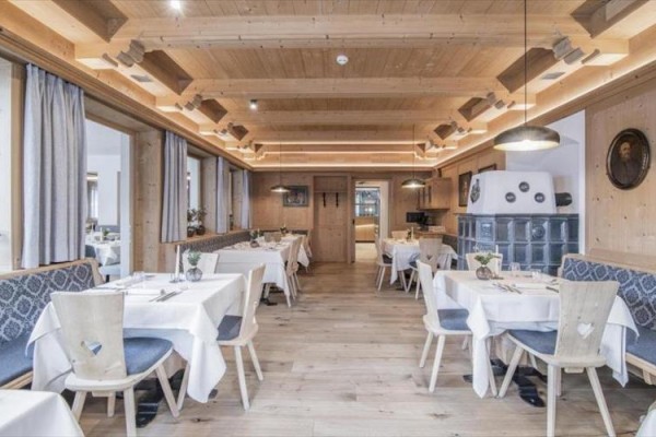 Interiér restaurace s dřevěnými obklady, bílými ubrusy a proutěnými židlemi.