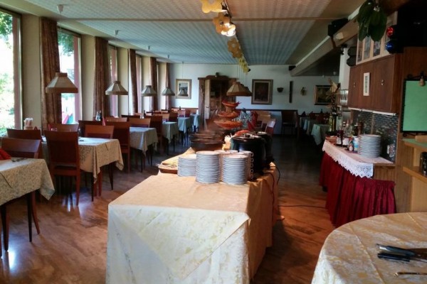 Restaurace s prostřenými stoly a bufetovým stolem uprostřed.