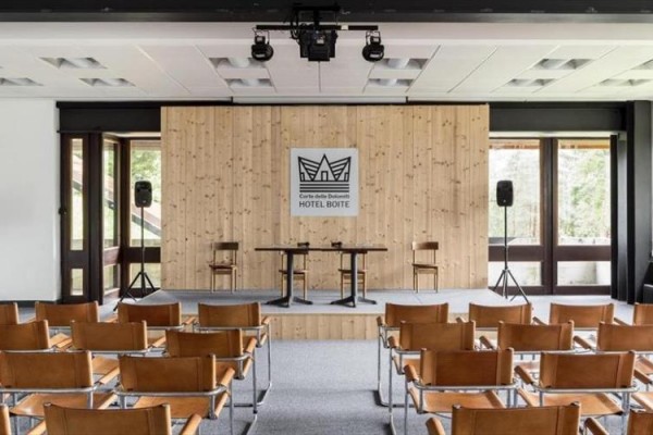 Konferenční místnost s dřevěným pódiem, dvěma židlemi a logem 