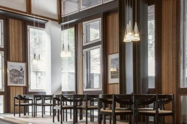 Moderní interiér kavárny s dřevěnými stěnami a závěsnými světly.