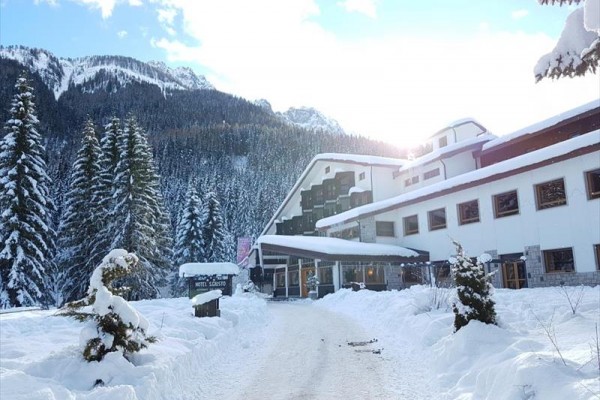 Zasněžený hotel obklopený zasněženými horami a stromy.