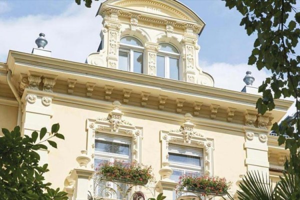 Zdobená fasáda historické budovy s květinami na balkonech.