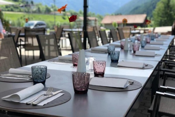 Stůl venkovní restaurace s prostíráním, sklenicemi a ubrousky.