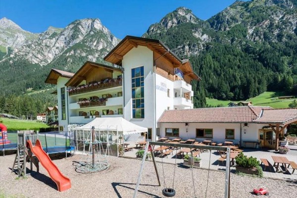 Moderní hotel s dětským hřištěm na pozadí hor.