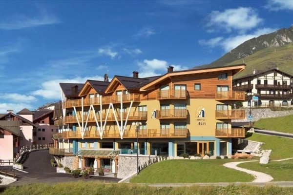 Horský hotel s dřevěnými balkony na svahu.