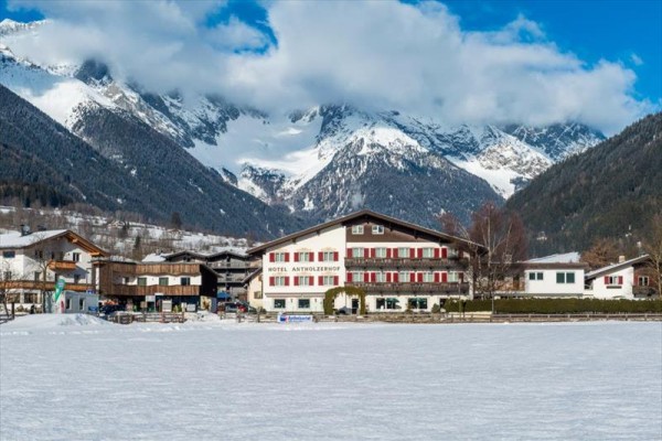 Hotel v zasněžené krajině s horami v pozadí.