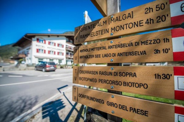 Dřevěné turistické směrovky u cesty s rozcestníkem na různé cíle včetně Grente a Rammelstein.