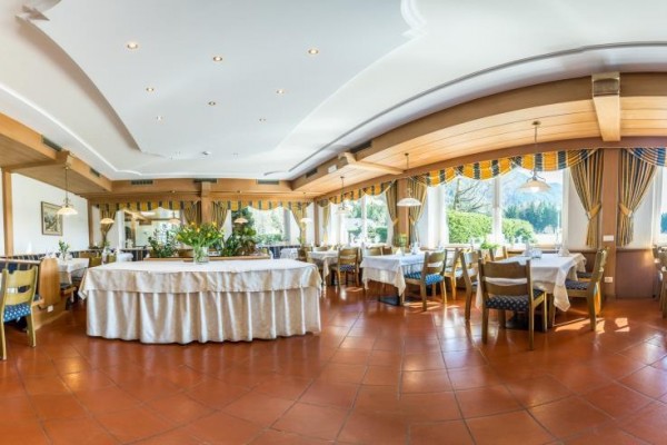 Elegantní restaurace s prostorným uspořádáním stolů a velkými okny s výhledem na přírodu.  