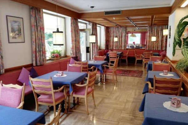 Restaurace s dřevěným nábytkem a modrými ubrusy na stolech. 