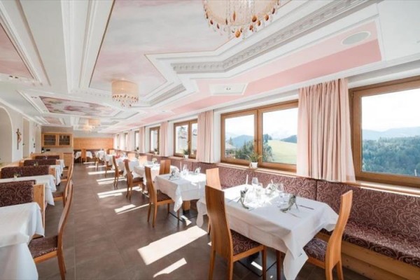 Světlá restaurace s velkými okny s výhledem na krajinu, prostřené stoly a židlemi z lehkého dřeva.  