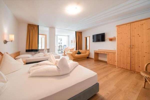 Moderní ložnice s manželskou postelí, dřevěným obložením a velkým oknem s červenými závěsy.