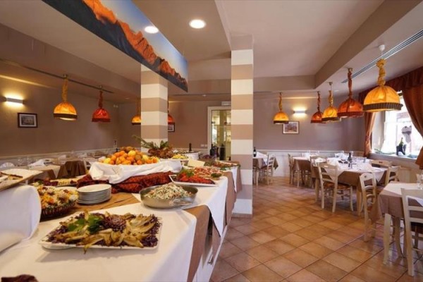 Restaurace s řadou stolů a bufetem naplněným jídlem.