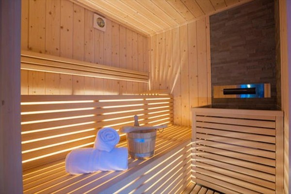 Dřevěná sauna s lavicí, dekou a kbelíkem uvnitř.