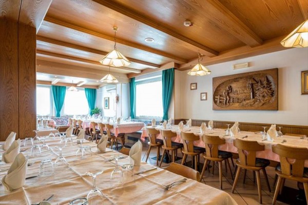 Prostorná restaurace s dřevěným obložením, prostřenými stoly a modrými závěsy.