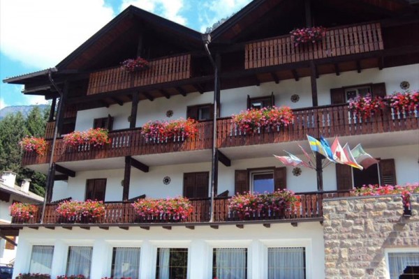 Budova s dřevěnými balkony a květinami na parapetech.
