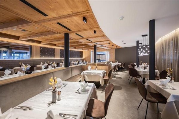 Moderní restaurace s dřevěným stropem a prostřenými stoly.