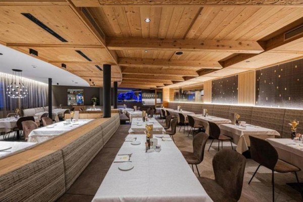Elegantní restaurace s dřevěným stropem a stoly s bílými ubrusy.