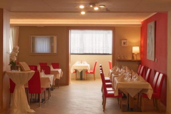 Interiér elegantní restaurace s červenými židlemi a prostřenými stoly.