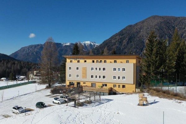 Budova hotelu na zasněžené krajině s horami v pozadí.