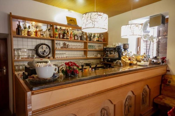 Bar s poličkami plnými lahví alkoholu a sklenicemi vedle kávovaru.