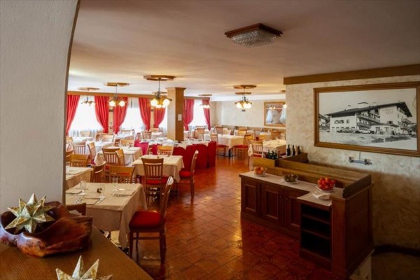 Restaurace s dřevěným nábytkem a červenými závěsy.