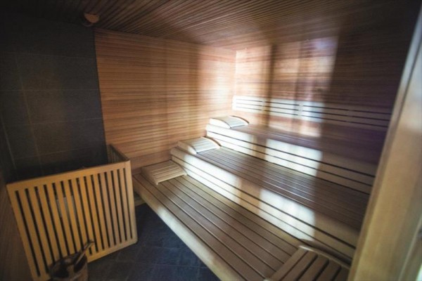 Dřevěná sauna s lavicemi a kamny.