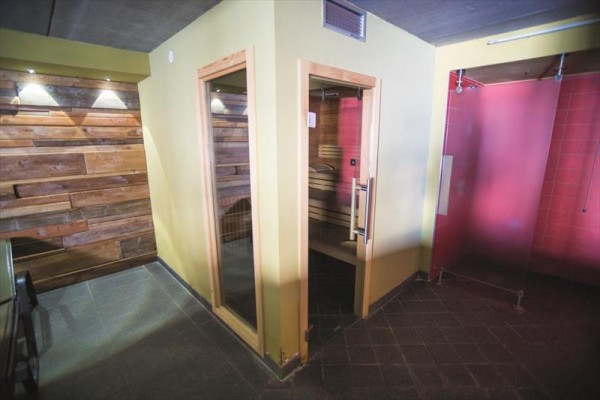 Sauna v místnosti se dřevěným obložením a sprchovým koutem.