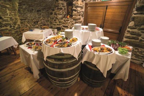 Hostina na stolech z dřevěných sudů v rustikální místnosti.  
