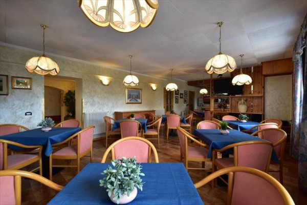 Restaurace s modrými ubrusy, růžovými židlemi a visícími lampami.