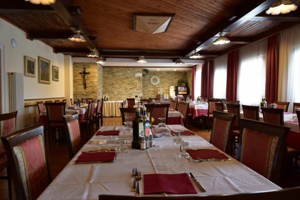 Restaurace s dřevěným stropem a připravenými stoly s červenými ubrusy.
