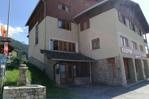 Budova hotelu s restaurací v horské oblasti pod modrou oblohou.