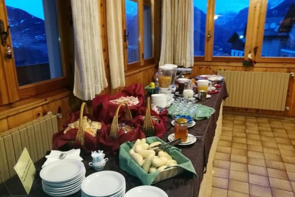 Bufetový stůl s jídlem a nápoji u okna s výhledem na hory.
