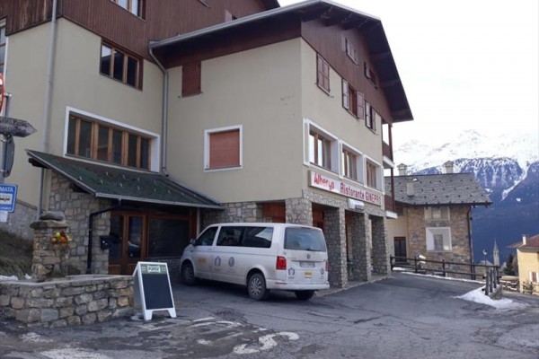 Budova restaurace v horské oblasti s bílou dodávkou zaparkovanou před vchodem.