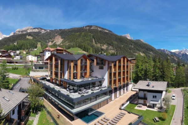 Moderní hotel v horské krajině se zasněženými vrcholy v pozadí.