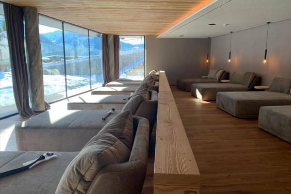 Moderní relaxační místnost s panoramatickými okny a pohodlnými lehátky.