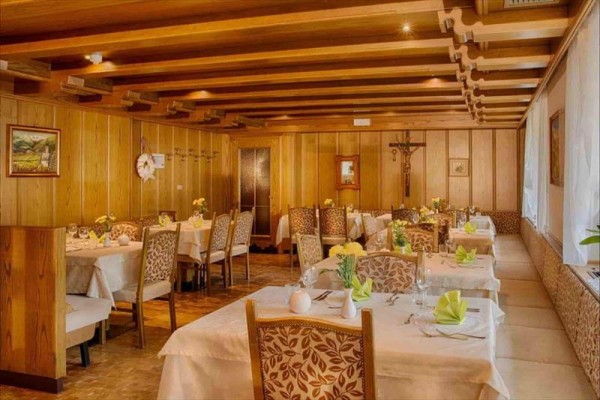 Interiér tradiční restaurace s dřevěným obložením a prostřenými stoly.