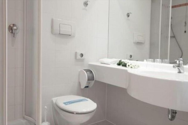 Moderní koupelna s toaletou, sprchovým koutem a umyvadlem se zrcadlem.