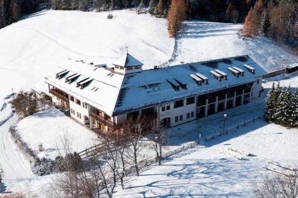 Velká budova obklopená zasněženou krajinou a stromy.