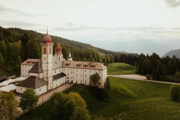 Klášter obklopený zelenými loukami a lesy v horské krajině.  