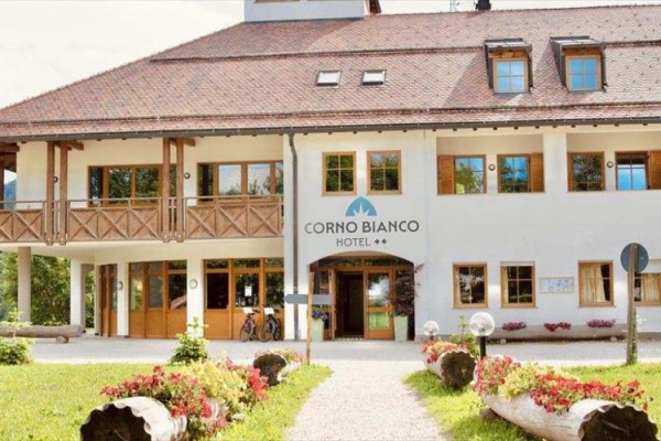 Hotel Corno Bianco s dřevěnými prvky a květinami před vstupem.