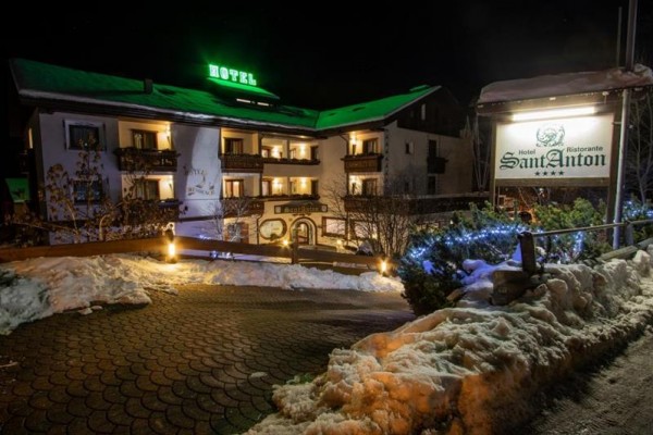 Noční pohled na osvětlený hotel se zasněženou krajinou a nápisem Hotel Sant Anton.