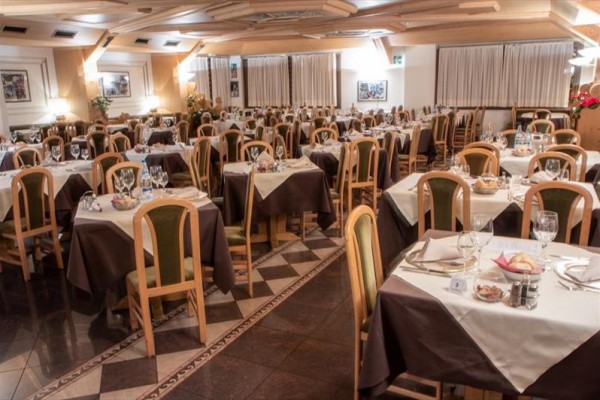 Prostorná restaurace s připravenými stoly a hnědými ubrusy.  