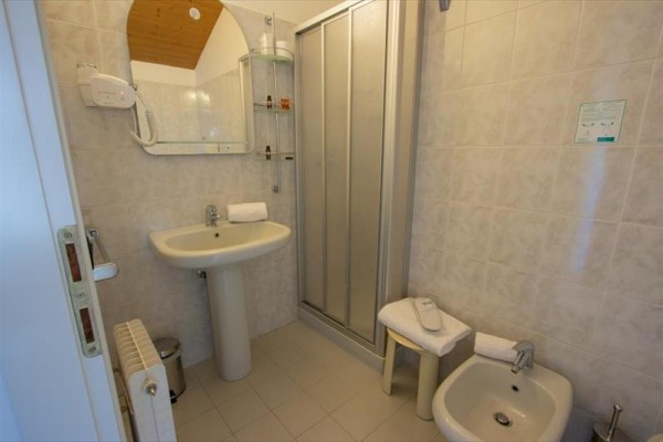 Moderní koupelna s umyvadlem, sprchovým koutem, bidetem a dekorativním zrcadlem.