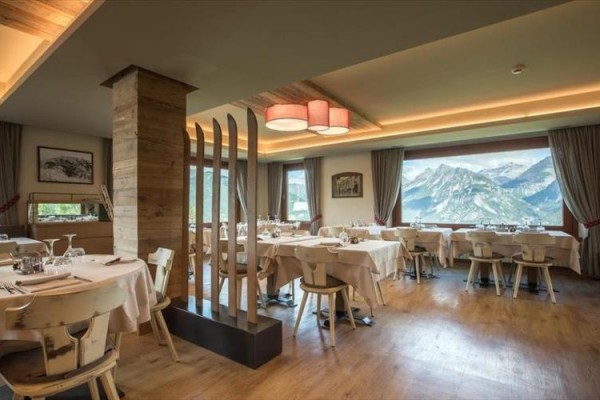 Restaurace s dřevěným nábytkem a výhledem na hory.