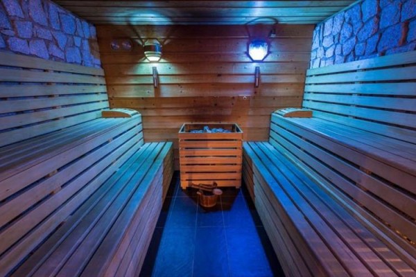 Dřevěná sauna s osvětlením a lavicemi na obou stranách.