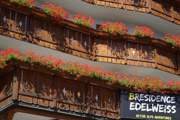 Balkony s dřevěným zábradlím zdobené květinami a nápisem 