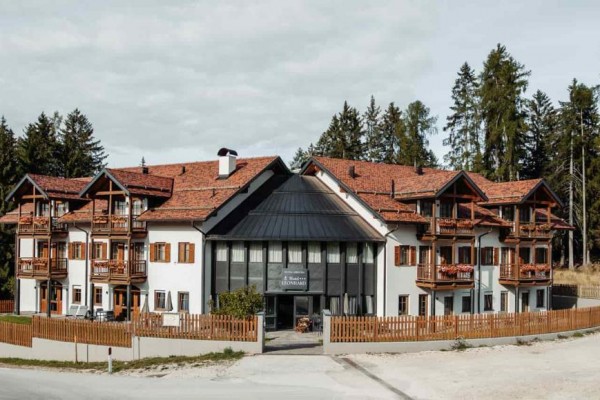 Hotel s dřevěnými balkóny obklopený lesem.