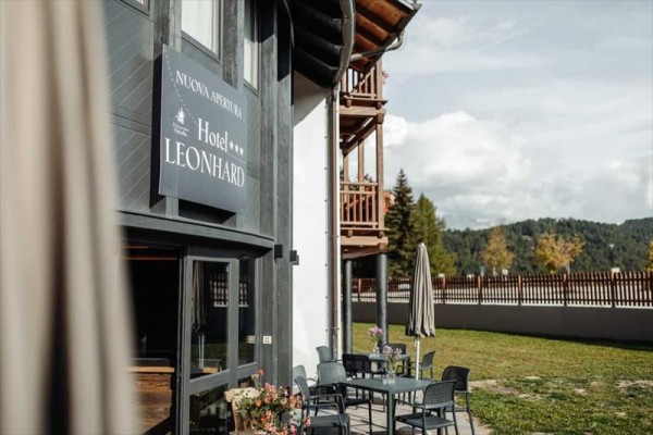 Venkovní posezení u hotelu s názvem Leonhard v horském prostředí.