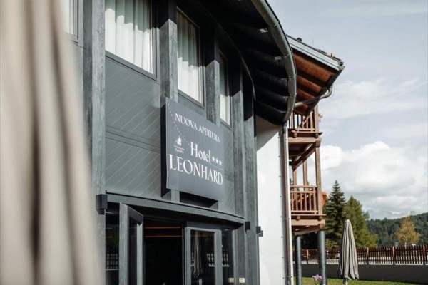 Vchod do hotelu Leonhard se dvěma hvězdičkami a dřevěným balkonem.