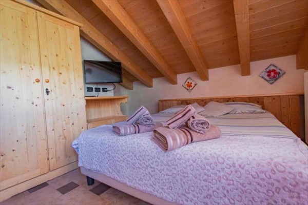 Moderní kuchyň s dřevěnými skříňkami, spotřebiči a jídelním stolem s květinou.